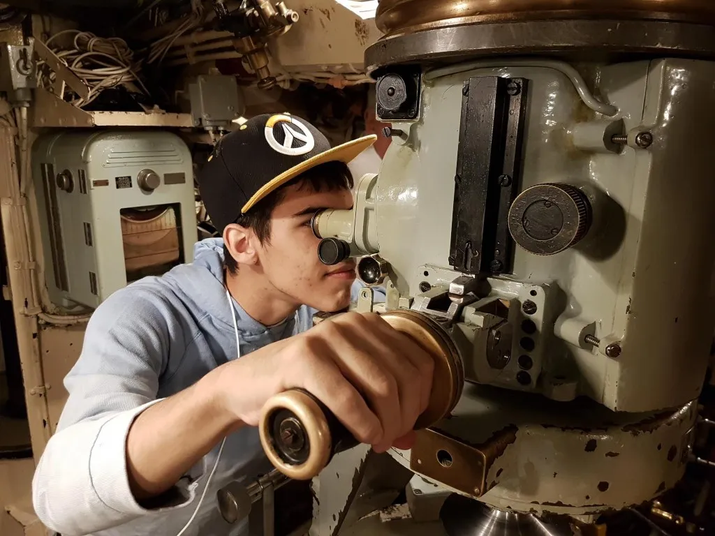 Teen Tech Camper during a Bridge Weekend trip inside a submarine looking through a periscope