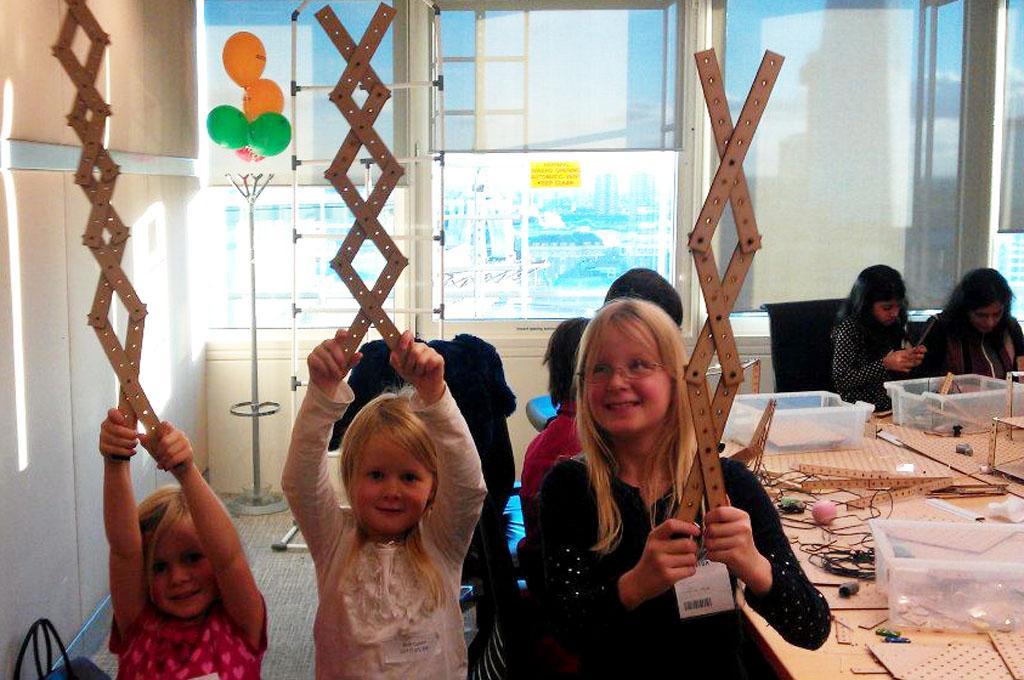 Two children and an adult using a Tech Camp construction kit to make scissor mechanisms